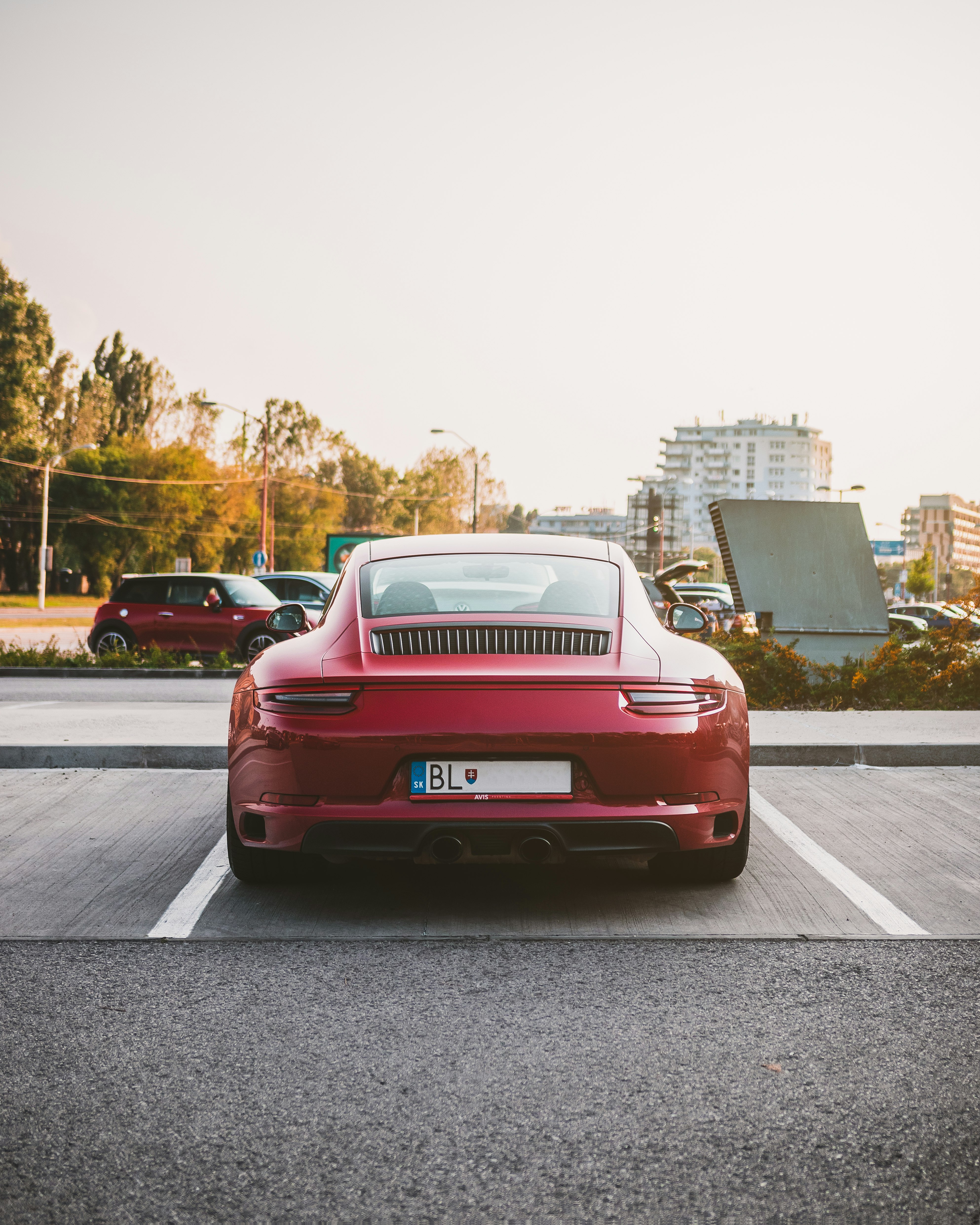 red vehicle parked on concrete pavement at daytime